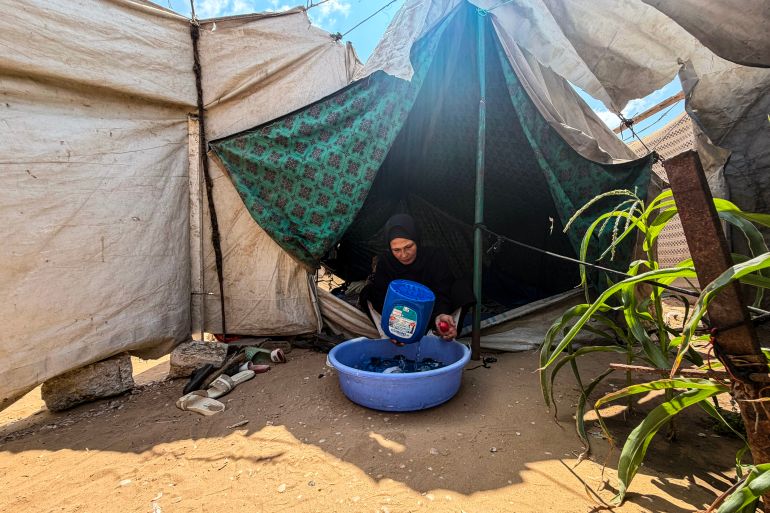 Eman Shamia washing her children’s clothes using a makeshift method