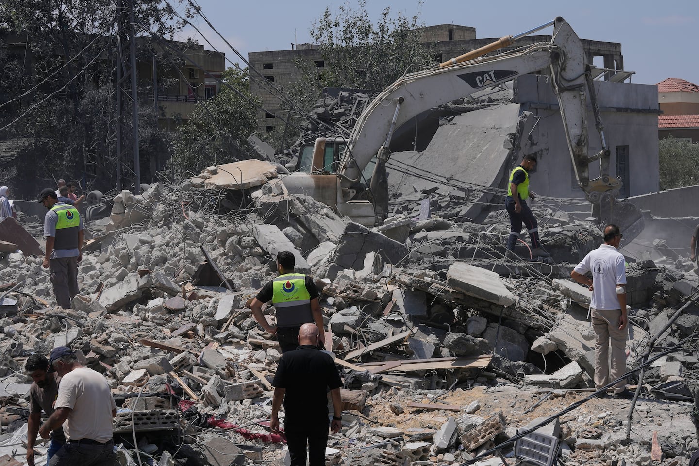Rescue workers and others gathered at a destroyed house that was hit by an Israeli airstrike in Deir al-Zahrani village, southern Lebanon, on Saturday.
