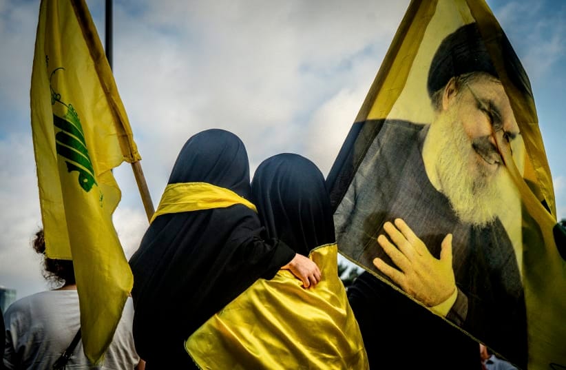 A woman and a child hold Hezbollah flags, including one bearing a portrait of slain Hezbollah leader Hassan Nasrallah, during a protest in Riyad al-Solh Square in central Beirut, Lebanon, on August 7, 2026.
