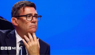 Andy Burnham looks pensive as he puts his hand to his chin and looks sideways.