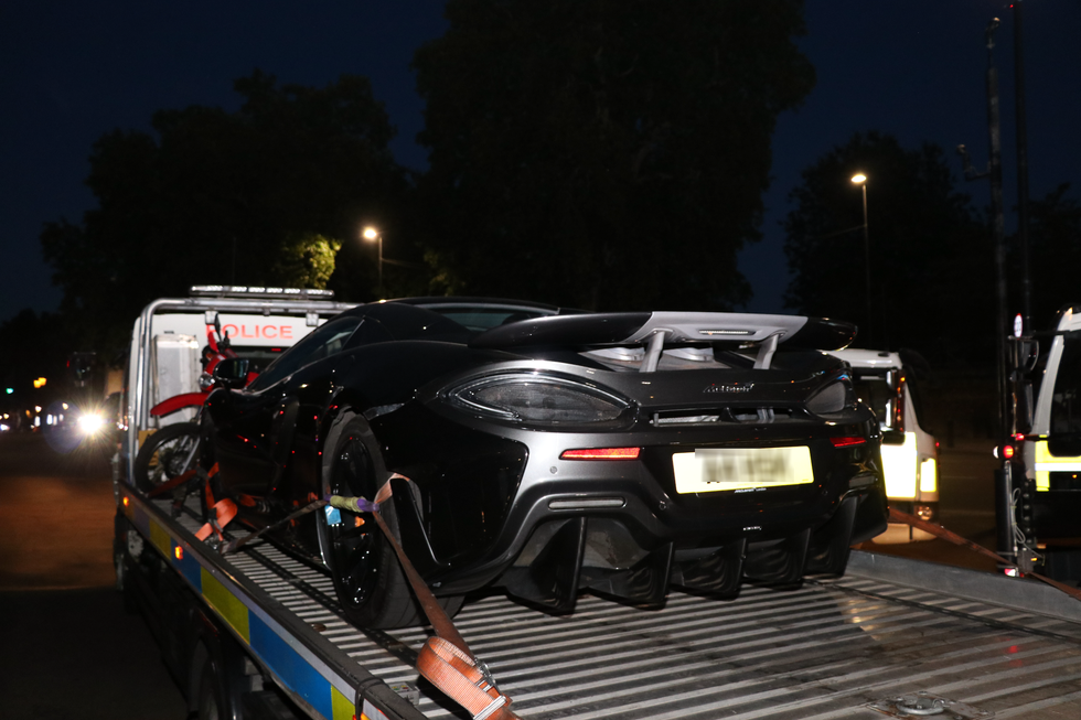 A McLaren 570a sports car being loaded onto a tow truck at night, with police vehicles in the background. A McLaren 570a sports car being loaded onto a tow truck at night, with police vehicles in the background.