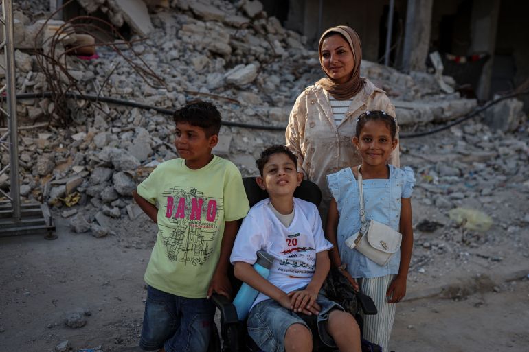 Warda Hijazi with her children: Saif, 13, who was severely injured and left paralysed during the war, her daughter Sarah, 9, and her son Ammar, 10 [Abdelhakim Abu Riash/ Al Jazeera]