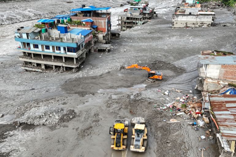 An aerial view shows workers using excavators to clear sludge following flash floods at Trishuli in Nepal’s Nuwakot district on August 27, 2026