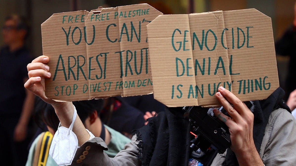 A person holds anti-Israel carboard signs