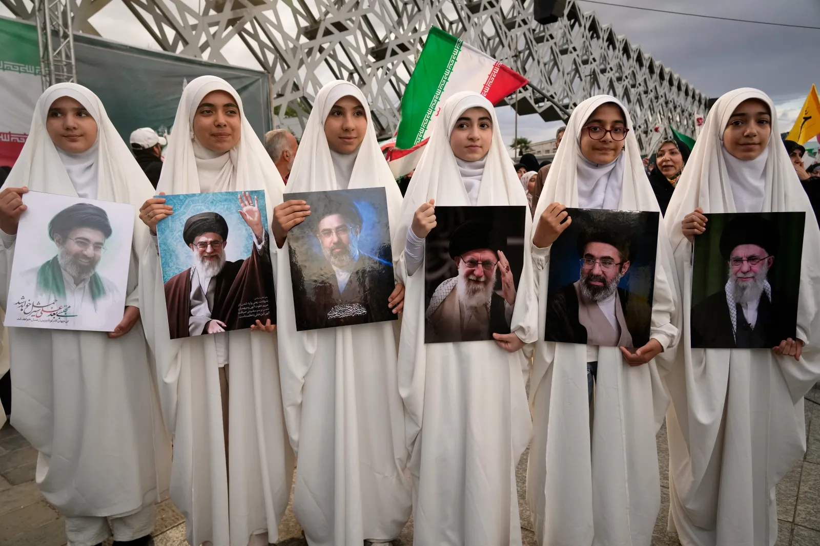 A group of girls holds portraits of Iran's Supreme Leader Ayatollah Mojtaba Khamenei and his late father, former Supreme Leader Ayatollah Ali Khamenei, during a mass wedding ceremony for couples participating in the "Janfada" ("Sacrifice for Iran") pro-government campaign in Tehran