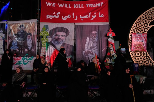 Iranian pro-government demonstrators sit beneath a banner reading in English and Farsi, "We will kill Trump," during a pro-government gathering at a square in Tehran, Iran, Tuesday, July 28, 2026. (AP Photo/Vahid Salemi)