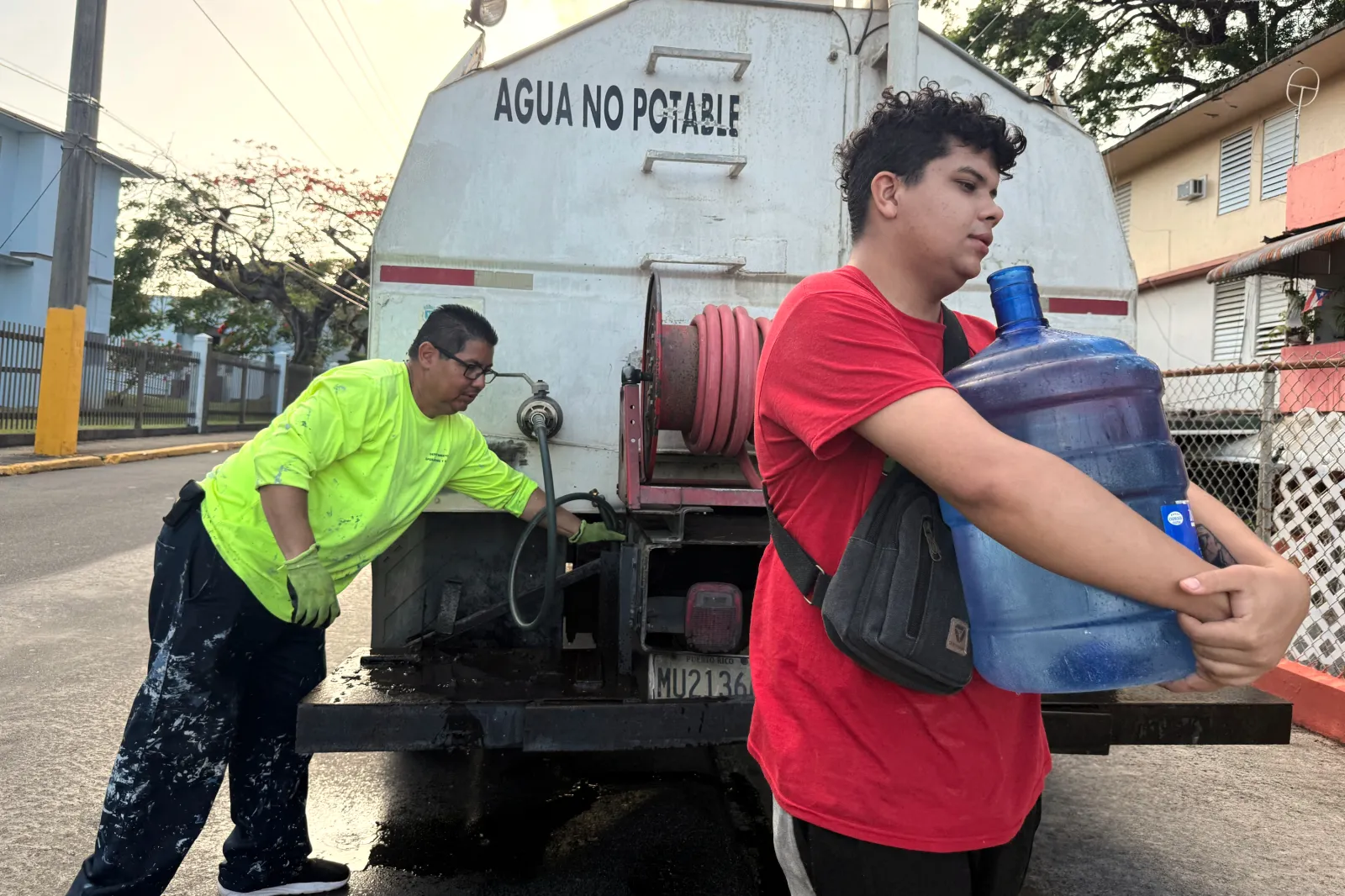 Bryan Pérez hauls a five-gallon water jug to his apartment in the Villa Kennedy public housing complex in San Juan, Puerto Rico, on June 10. (AP Photo/Danica Coto, File)