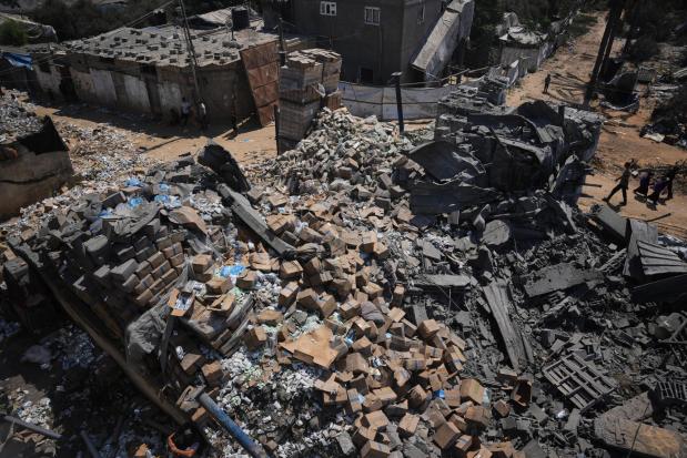 Palestinians walk past a food-aid warehouse damaged in an Israeli airstrike.
