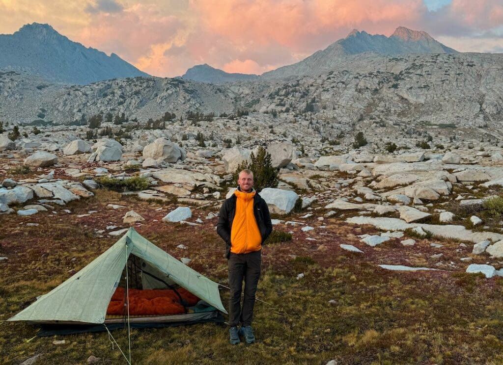 Jake standing by a tent in mountains