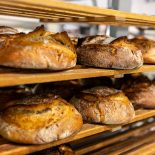 Cooling rack filled with freshly baked artisanal breads in bakery - stock photo