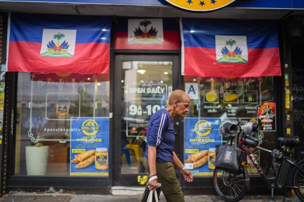 A woman walks past a restaurant displaying Haitian flags in the Little Haiti neighborhood of Brooklyn, New York, on July 29, 2026. (Photo by Ryan MURPHY / AFP via Getty Images)
