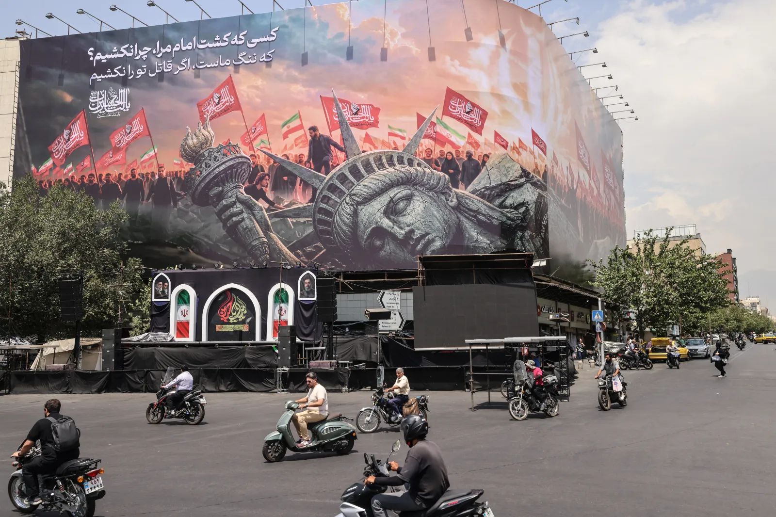 Iranians drive past an anti-U.S. billboard at Enghelab Square in central Tehran on August 3, 2026.