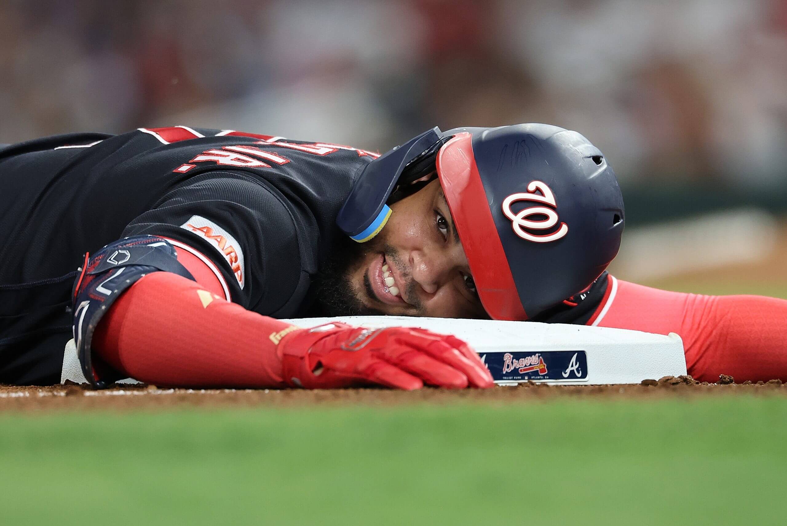 Luis García Jr. of the Washington Nationals rests his head on third base.