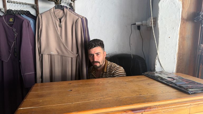 Firas Zaqloul sits in a clothing store trying to figure out a way to pay for his items because the seller won’t accept his cash