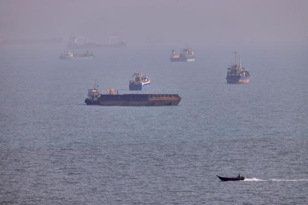 A small boat sails past vessels in the Strait of Hormuz.