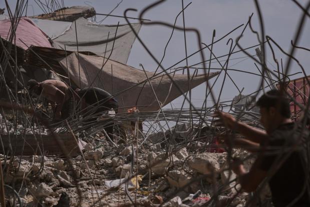 Palestinians remove iron from the rubble of buildings destroyed by Israeli airstrikes.