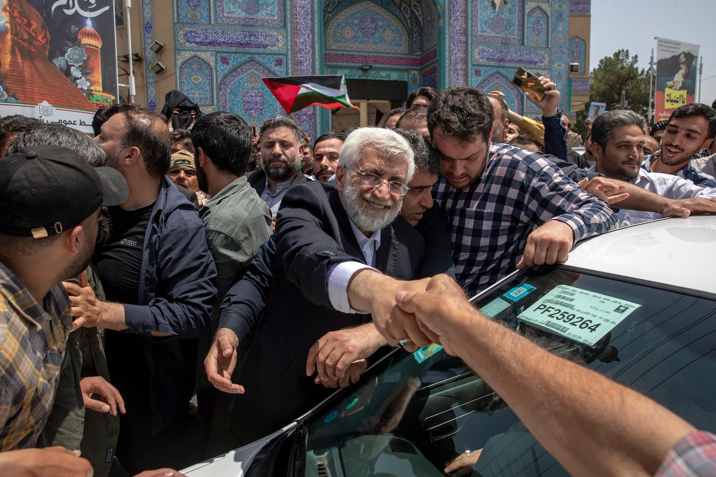 Candidate for Iran's presidential election Saeed Jalili, a hard-line former nuclear negotiator, shakes hands with a supporter after casting his vote for the presidential runoff election in Qarchak, near Tehran, Iran, on July 5, 2024.