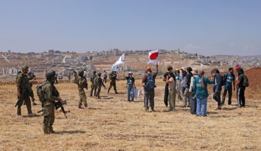 Activists hold flags next to Israeli soldiers as they accompany Palestinian landowners to their property, which is at risk of being confiscated by Israeli settlers, in Beit Sahur, south of Bethlehem, in the occupied West Bank on Aug. 14, 2026. Violence against Palestinians by Israeli settlers in the West Bank has increased dramatically since the Oct. 7, 2023 attack on Israel by Hamas from the Gaza Strip. More than 500,000 Israelis live in settlements in the West Bank, which are illegal under international law, among some three million Palestinians in the territory.