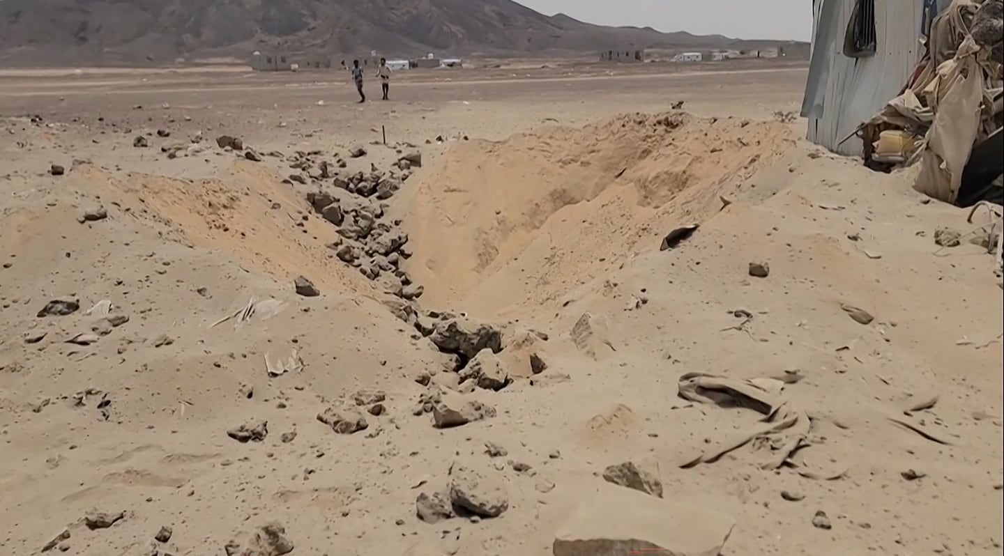 This frame grab taken from AFPTV video footage on Aug. 7, 2026, shows people walking near the damage at Mail al-Saila internally displaced camp (IDP) on the outskirts of Marib following a reported Houthi ballistic missile attack on the government-held city of Marib early Aug. 7, amid an escalation in hostilities. The strategic province of Marib is split between the Houthis and the government, which controls the city of Marib as well as the surrounding oil fields and facilities.