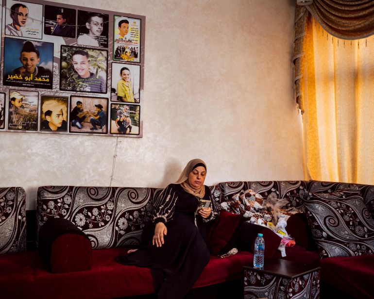 Suha Abu Khdeir sits underneath pictures of Mohammed Abu Khdeir in the living room of her home, in Shuafat neighbourhood of Occupied East Jerusalem. Mohammed was kidnapped outside his home and murdered by Israeli Jewish citizens on July 2nd 2014 [Lucien Lung/Al Jazeera]