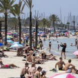 Tourists gather on Palma's Beach in Palma de Mallorca on July 18, 2025. Spanish company Amadeus, the world's leading travel booking provider, saw its profits jump by 12% in the first half of the year, driven by the strength of the tourism and air transport sectors, which boosted its revenues, according to its results published on July 31, 2025. (Photo by JAIME REINA / AFP) (Photo by JAIME REINA/AFP via Getty Images)