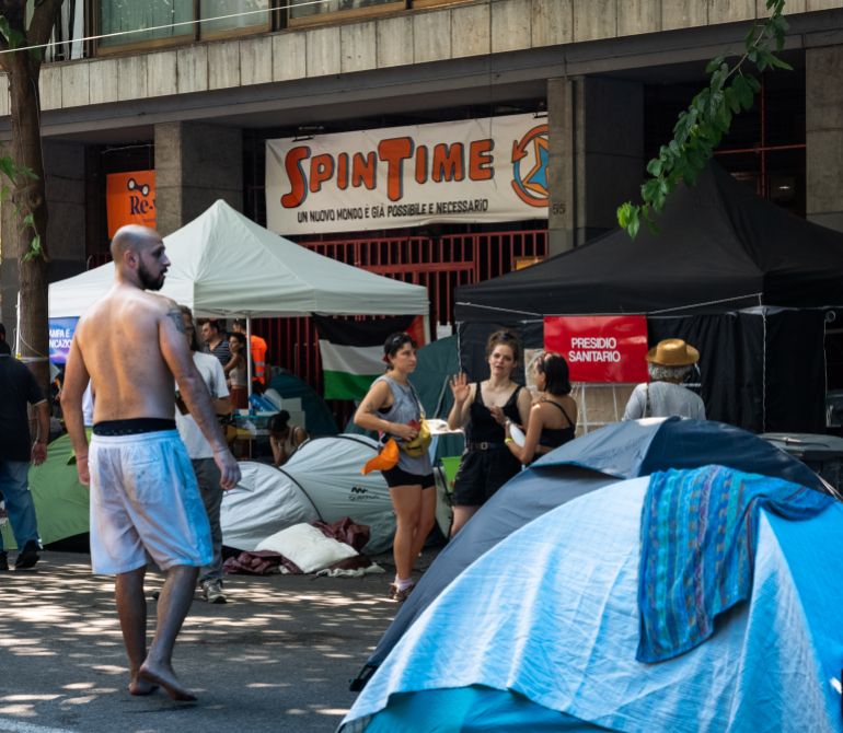 SpinTime_Manda_03 — A medical point set up by volunteers stands among the tents outside Spin Time, where residents have been sleeping since the building was sealed, Rome, August 6, 2026.