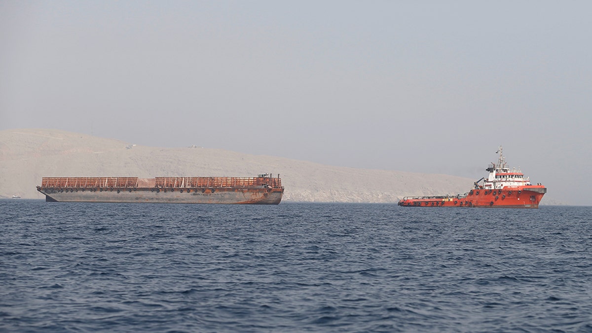 FILE PHOTO: A tug boat moves cargo towards the Strait of Hormuz, in Musandam province, Oman, July 20, 2018. Picture taken on July 20, 2018. REUTERS/Hamad I Mohammed/File Photo - RC1549765850