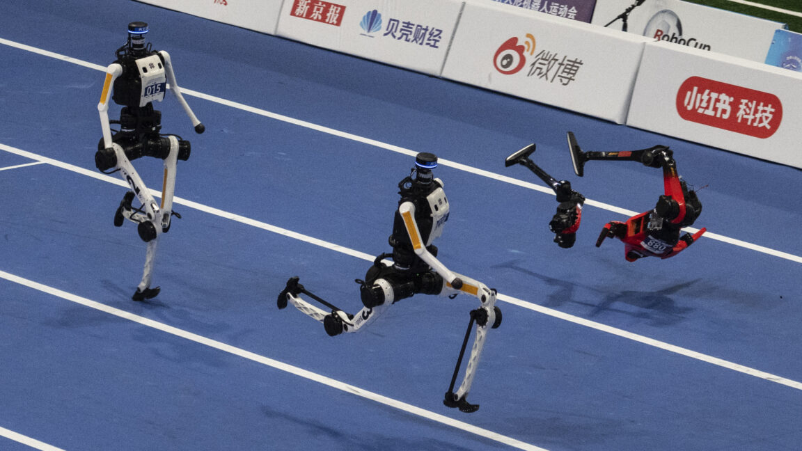An Honor humanoid robot breaks into pieces as it runs next to two Tian Gong Ultras, center and left, in the second heat of the large robot category of the 100 meter at the 2nd World Robot Games at National Speed Skating Oval on August 25, 2026 in Beijing, China.