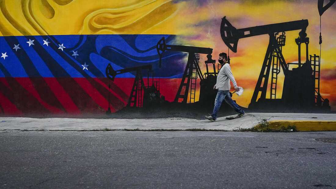 A man walks past a mural featuring oil pumps and wells in Caracas, Venezuela, as the country faces the prospect of the U.S. reimposing oil sanctions.