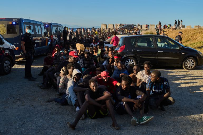 Migrants who crossed from Morocco into Spain line up for food distribution on a beach in the Spanish enclave of Ceuta, Monday, Aug. 3, 2026. (AP Photo/Bernat Armangue)