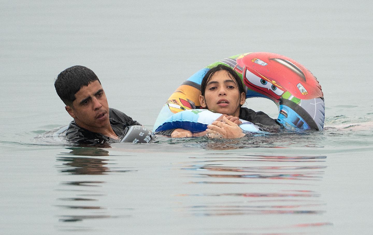 Migrants swim around a border barrier with Morocco to enter the Spanish enclave of Ceuta in North Africa in July 31, 2026, two of the roughly 50,000 people who crossed into the territory last week. More than 70 people died in the crossing.