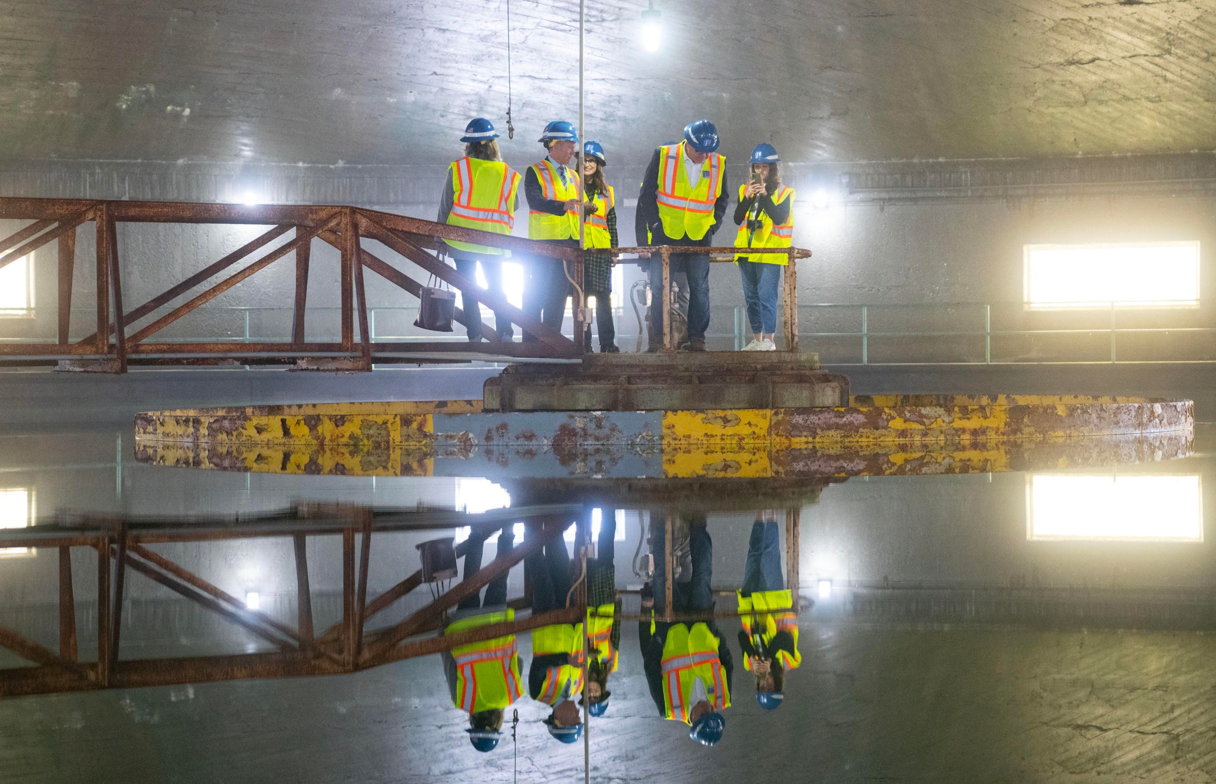 A group including Governor Tim Walz, Lieutenant Governor Peggy Flanagan, Saint Paul Mayor Melvin Carter and General Manager Patrick Shea stand in the center of a lime softening clarifier during a tour of McCarrons Water Treatment Plant on January 26, 2023 at St. Paul Regional Water Services in Maplewood, Minn.