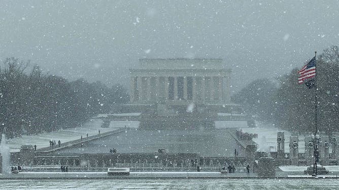 05 December 2025, USA, Washington: Snow lies in front of the Lincoln Memorial (background) during the first snowfall of the winter season.