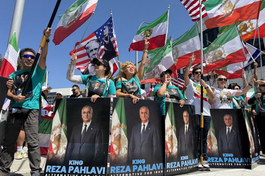 People wave US and pre-revolutionary Iranian flags as they protest the Iranian regime outside of Los Angeles Stadium in Inglewood, California, on June 7, ahead of the start of the 2026 FIFA World Cup.