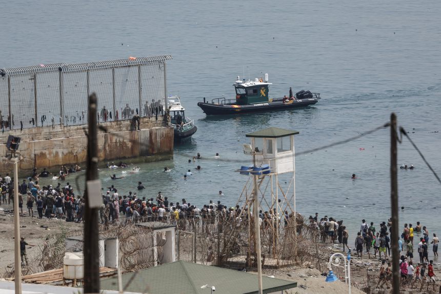 A photograph taken from the outskirts of the Moroccan town of Fnideq on the Morocco-Spain border shows Spanish Guardia Civil officers monitoring migrants attempting to reach Ceuta by swimming across the maritime border, on July 31.