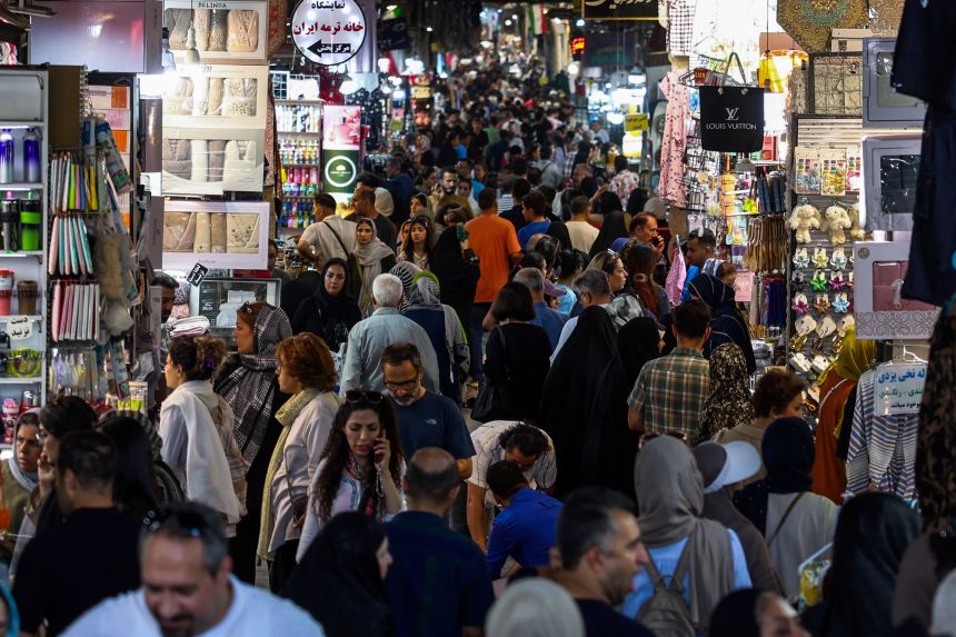 People walk past shops and browse for goods at the Grand Bazaar in Tehran on August 24. Oil prices fell earlier as investors braced for details of a US plan to isolate the Iranian economy that President Donald Trump billed as the 