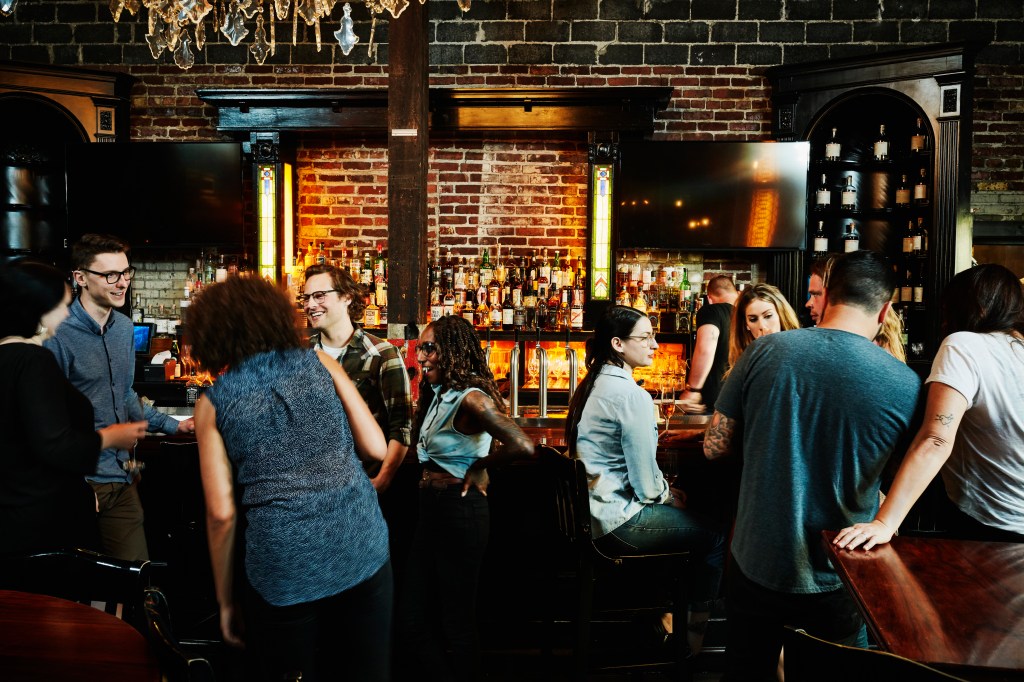 A group of friends sharing drinks in a busy bar.