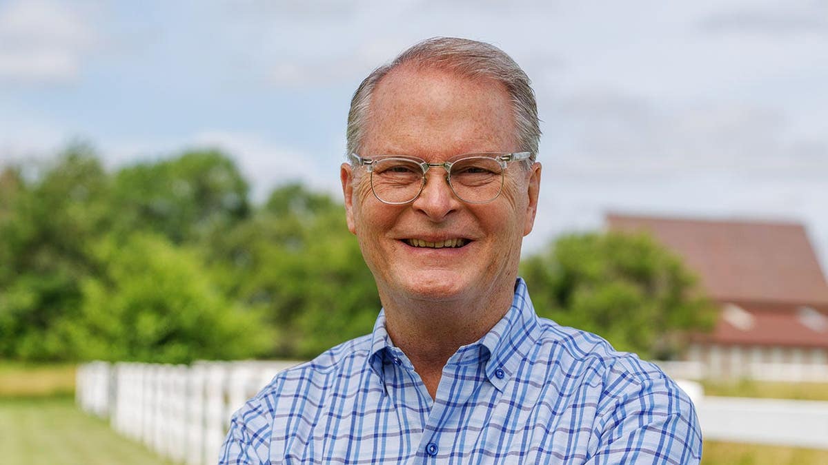Adam Hamilton standing in a field in front of a white fence