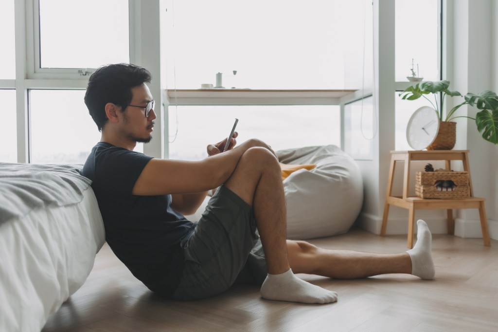 Lonely man using smartphone in his apartment.