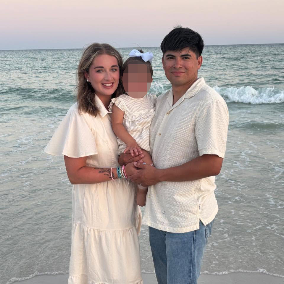 Sadie Flores, a school teacher, posing with a man and blurred-out child on a beach.