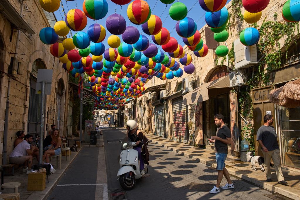 People walk under an art installation of colorful spheres in Jaffa, Tel Aviv, Israel.