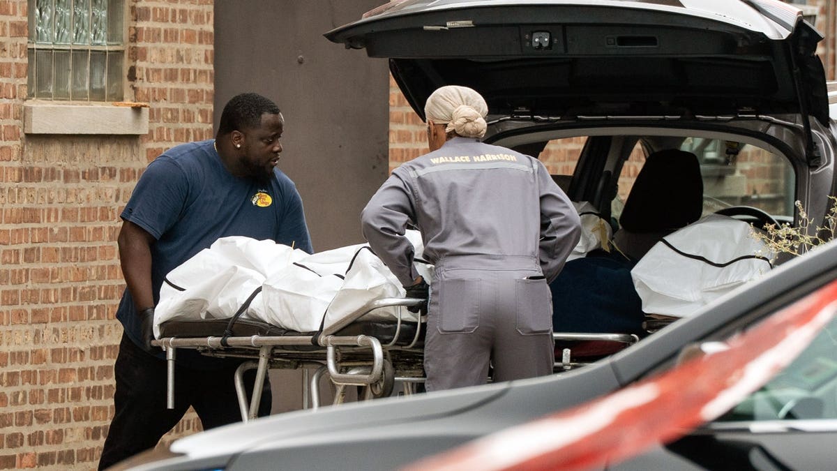 Workers load bodies into an SUV outside South Chicago Chapel