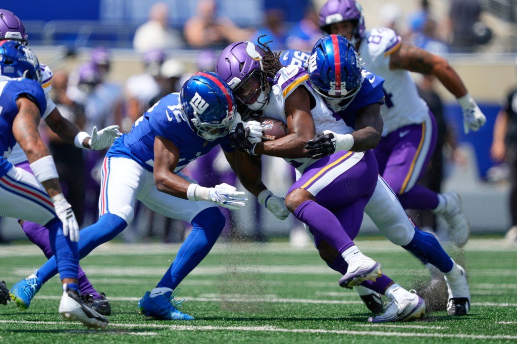 Minnesota Vikings running back Jordan Mason (27) is tackled by New York Giants linebacker Arvell Reese (52) and cornerback Colton Hood (12) during a preseason NFL football game.