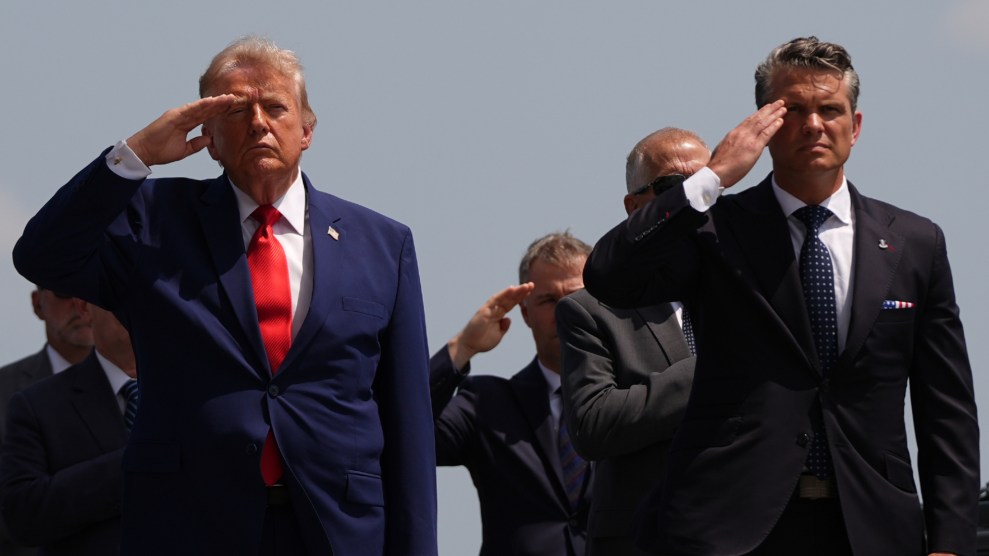 Donald Trump and Pete Hegseth, both dressed in dark suits are saluting with their right hands while standing outside. Four people are seen standing behind them.
