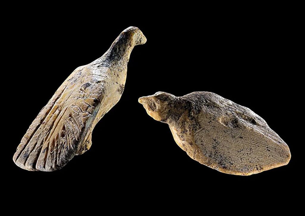 Ancient figurines carved into the shapes of birds against black background