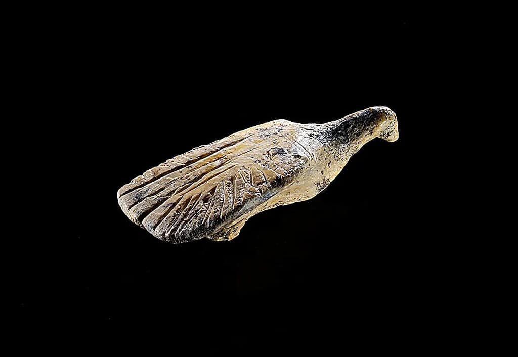 Ivory carved figurine of a bird on a black background