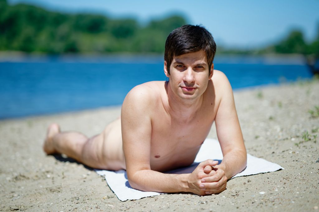 Mannheim city councillor Julien Ferrat lies naked on the sandy shore of Friesenheim Island.