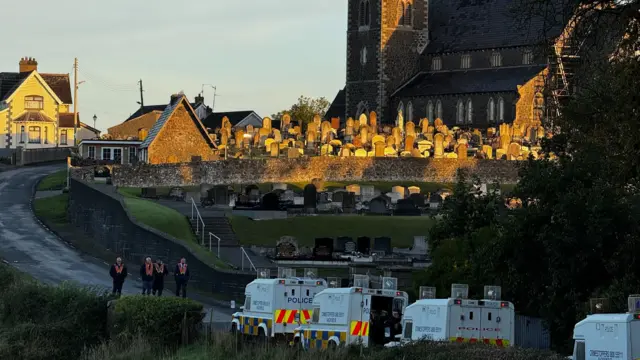 Four orangemen stand in front of four police landrovers