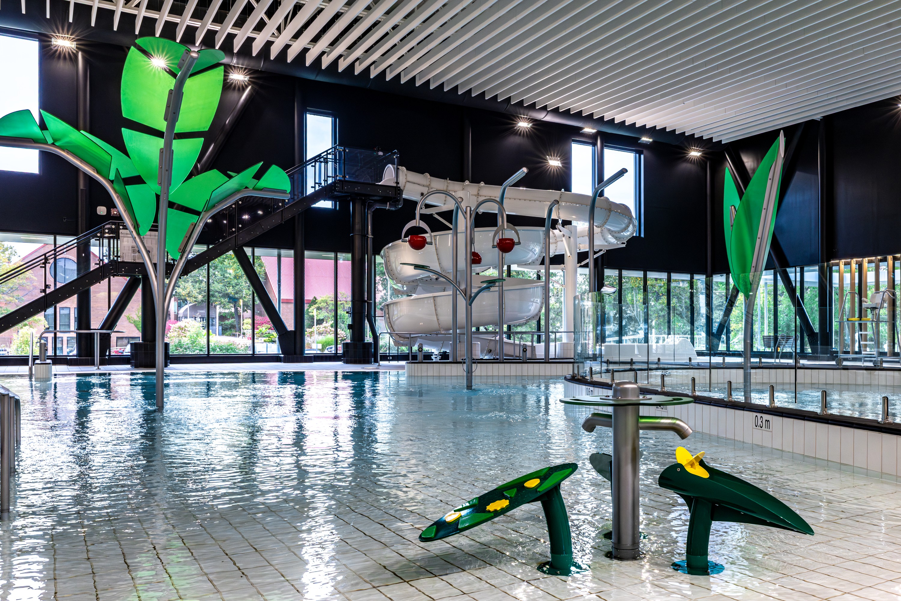 a recreational pool with a wading area, slide and water play features. 