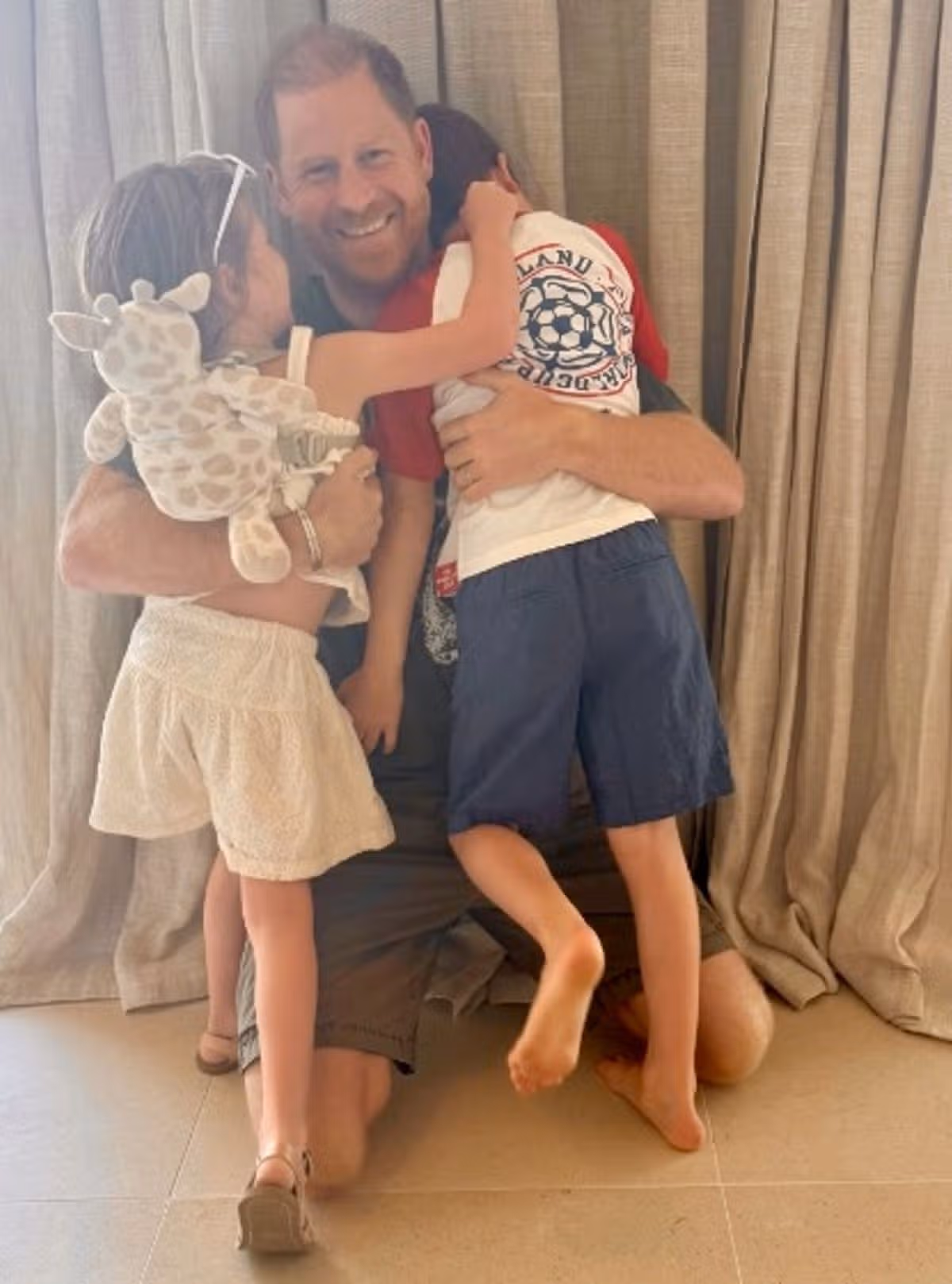 Harry smiling and hugging Archie and Lilibet